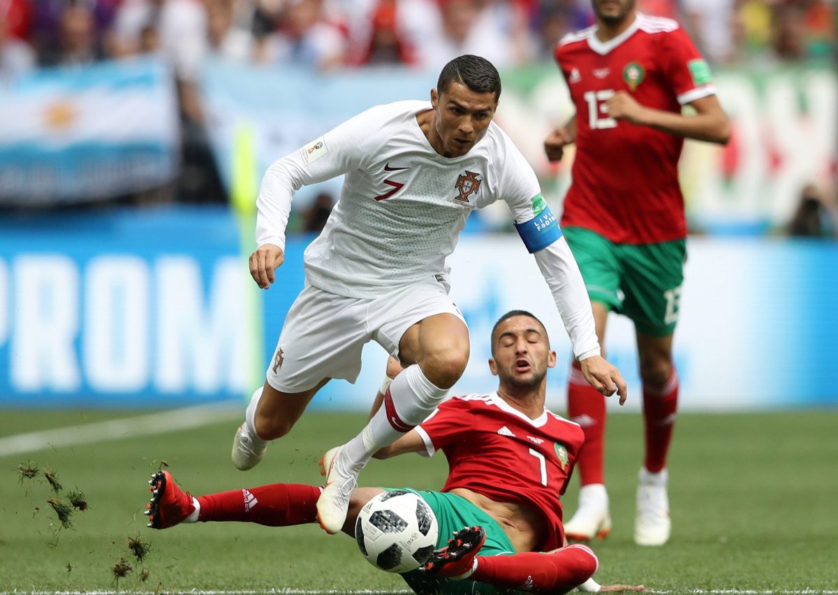 Cristiano Ronaldo of Portugal skips a sliding challenge from Hakim Ziyach of Morocco.